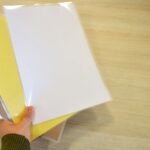 Worker,Grabbing,Some,Laminating,Pouches,With,Yellow,,Craft,And,White