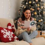 Happy,Young,Woman,Reading,Christmas,Greeting,Card,While,Sitting,On